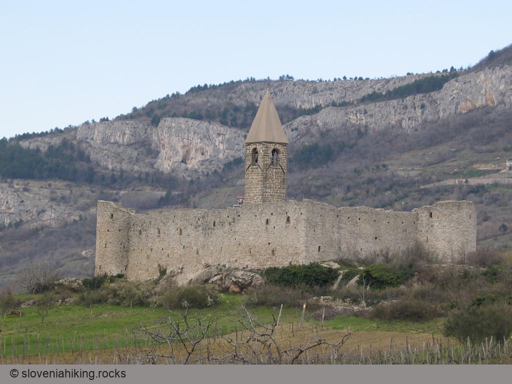 Cerkev v Hrastovljah, za njo skale Kraškega roba